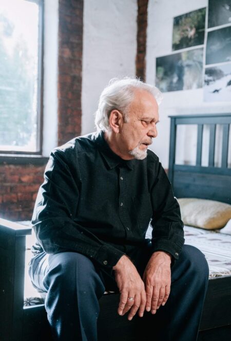 A tired old man sitting on a bed