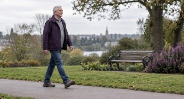 An older adult walking comfortably on a park path, illustrating gentle exercise for knee osteoarthritis